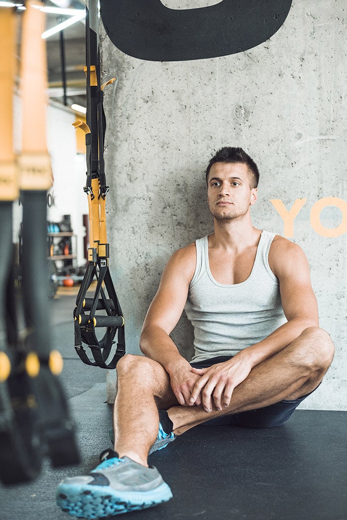 young-man-sitting-floor-fitness-club